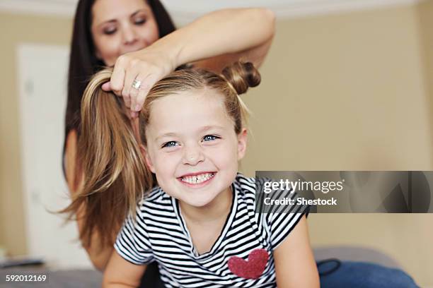 mother styling hair of daughter on bed - combing stock pictures, royalty-free photos & images