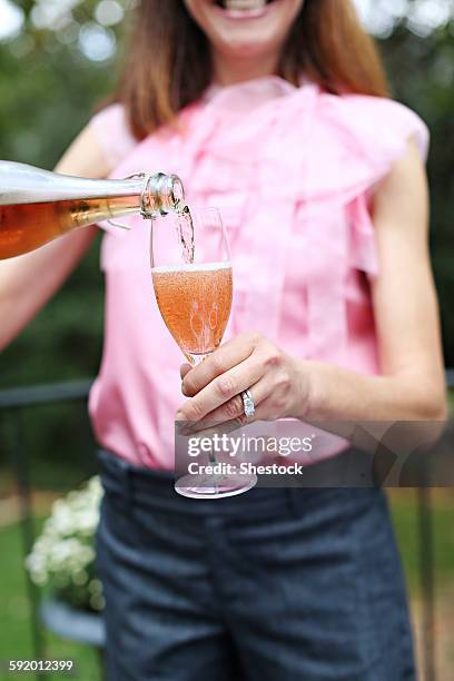 woman pouring glass of rose wine - single rose stockfoto's en -beelden