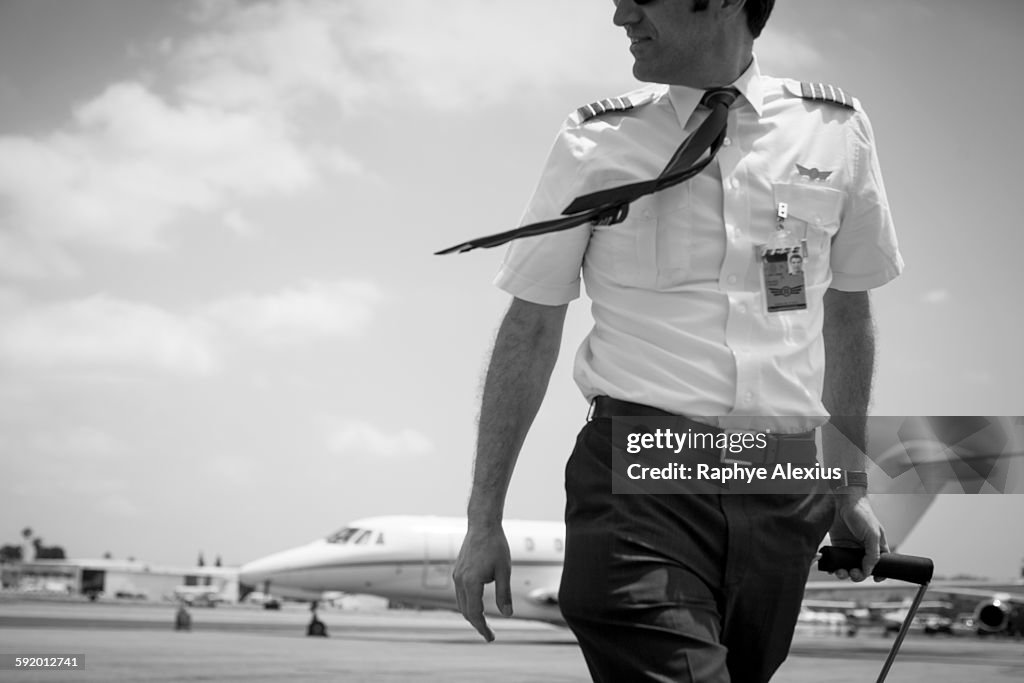 Black and white image of male private jet pilot arriving at airport