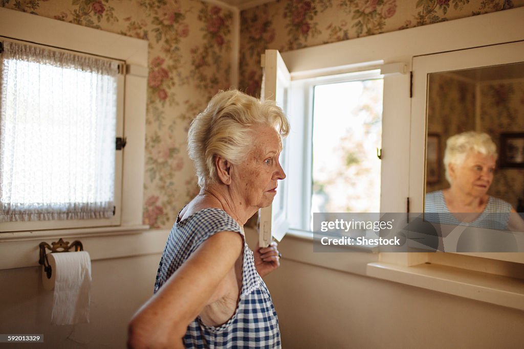 Older Caucasian woman examining herself in mirror