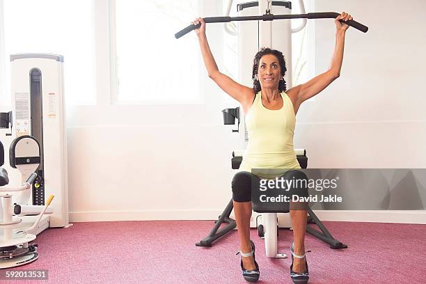 mature woman at gym on exercise machine - pectoral muscle stock pictures, royalty-free photos & images