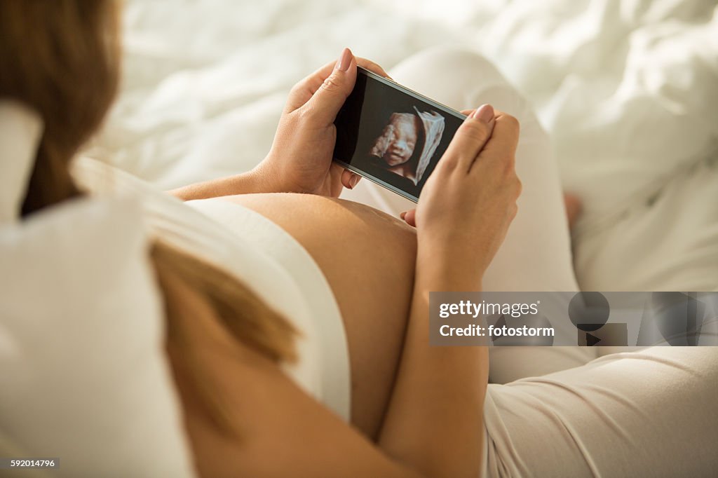 Pregnant woman looking at 3D ultrasound photo of her baby