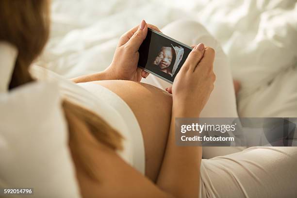 pregnant woman looking at 3d ultrasound photo of her baby - 3d ultrasound stock pictures, royalty-free photos & images