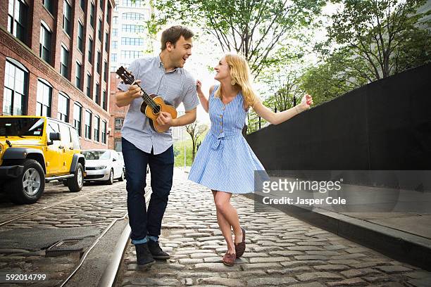 caucasian couple playing ukulele on city street - ukulele stock-fotos und bilder