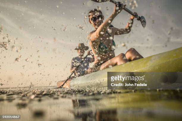 couple rowing canoe on still lake - canoe fotografías e imágenes de stock