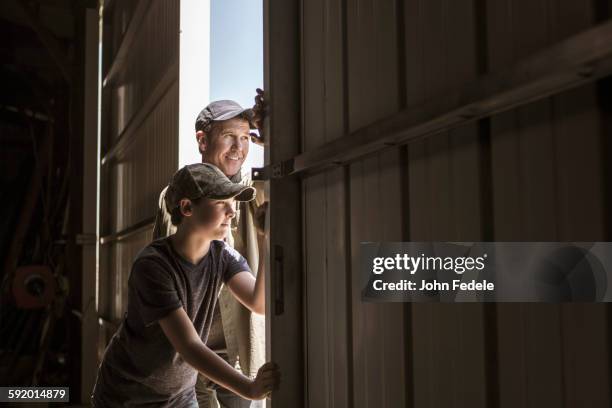 caucasian father and son opening barn door - doors of the 21st century ストックフォトと画像