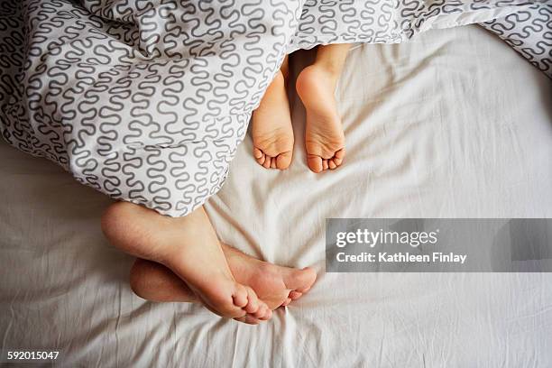 bare feet of father and young son lying in bed - bare feet stock-fotos und bilder