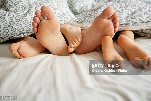 bare feet of father and two sons lying in bed - mens bare feet fotografías e imágenes de stock