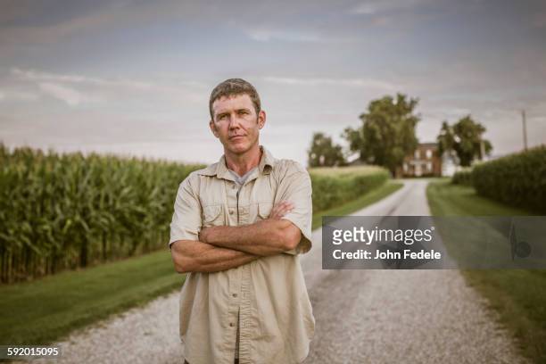 caucasian farmer standing on dirt road by corn field - endast medelålders män bildbanksfoton och bilder