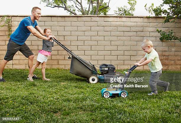 family mowing lawn in backyard - erwachsene imitieren stock-fotos und bilder