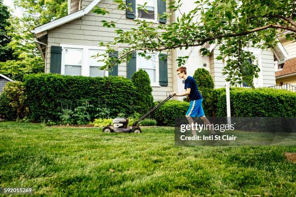 caucasian boy mowing front lawn - lawn mowing photos et images de collection