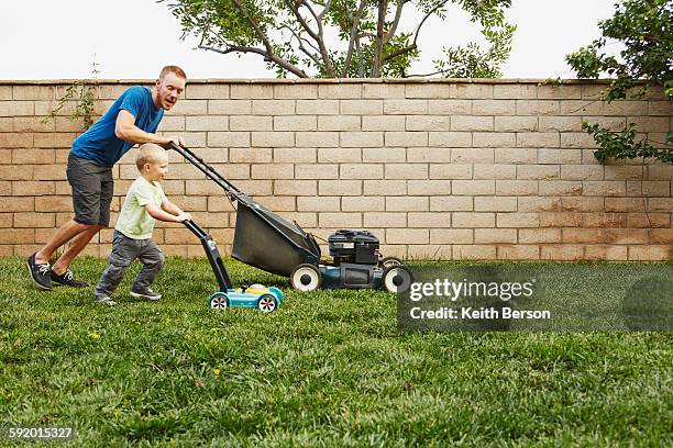 father and son mowing lawn in backyard - mowing lawn stock-fotos und bilder