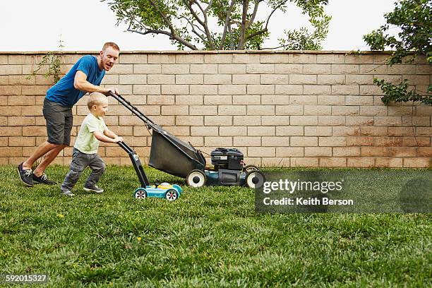 father and son mowing lawn in backyard - mowing stock pictures, royalty-free photos & images