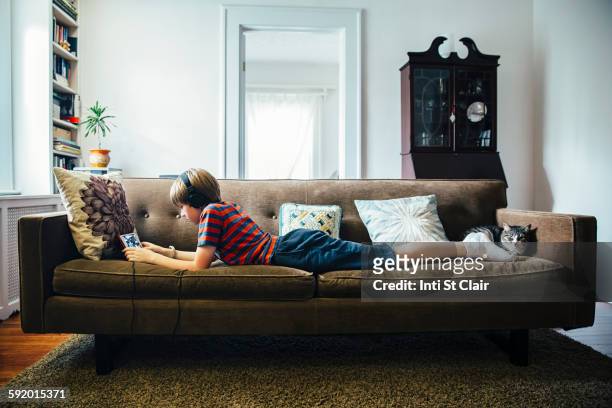 caucasian boy using digital tablet on sofa - boy ipod stock pictures, royalty-free photos & images