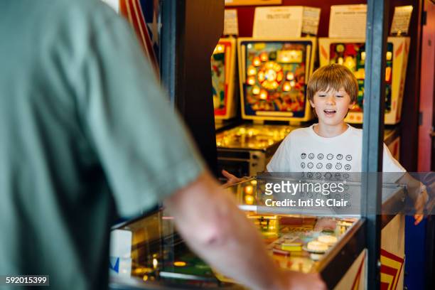 caucasian father and son playing game in arcade - pinball stock-fotos und bilder