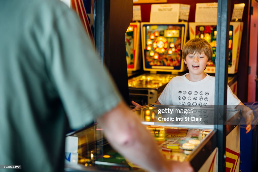Caucasian father and son playing game in arcade
