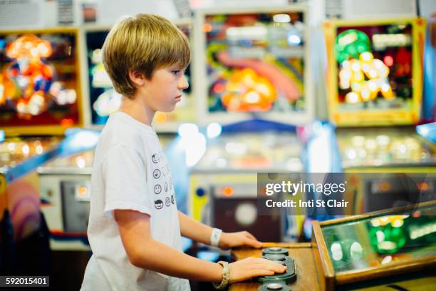 caucasian boy playing video game in arcade - pinball stock pictures, royalty-free photos & images