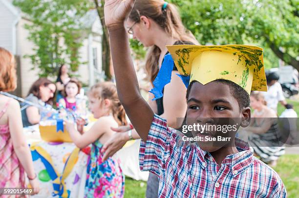 portrait of young boy at kindergarten graduation, wearing paper mortar board - graduation party stock-fotos und bilder