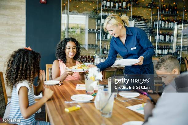 server bringing food for family in restaurant - serveur restaurant stock pictures, royalty-free photos & images