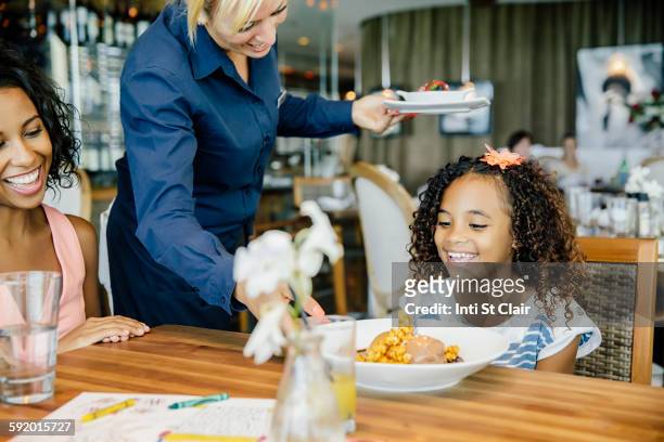 server bringing birthday dessert to girl in restaurant - restaurant kids stock-fotos und bilder