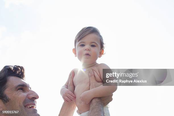 low angle view of father holding up son, looking at camera - santa clarita stock pictures, royalty-free photos & images