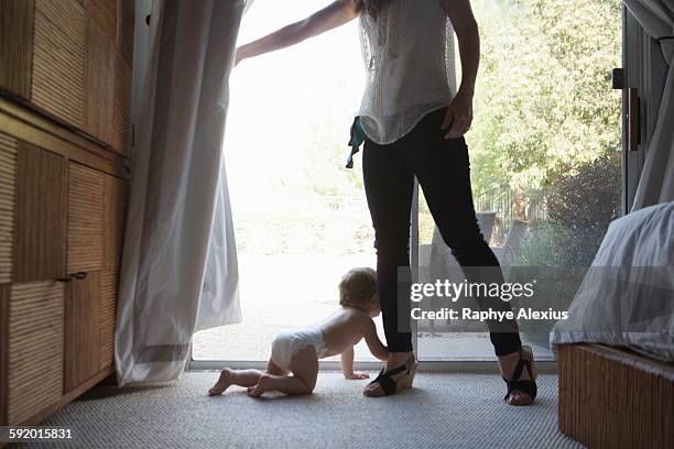 baby boy holding onto mothers leg in front of patio door - santa clarita stock pictures, royalty-free photos & images