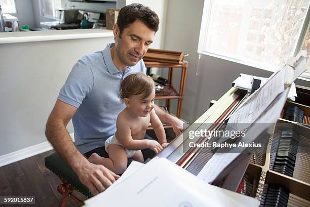 baby boy sitting on fathers knee playing piano - santa clarita stock pictures, royalty-free photos & images