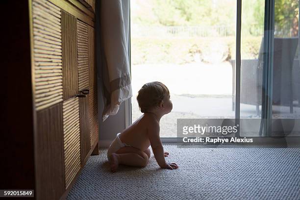 side view of baby boy sitting in front of patio doors, looking away - santa clarita stock pictures, royalty-free photos & images