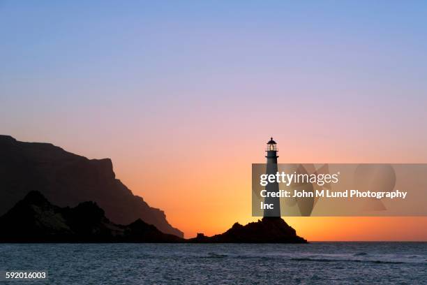 lighthouse on coastal cliffs under sunrise sky - lighthouse sunset stock pictures, royalty-free photos & images