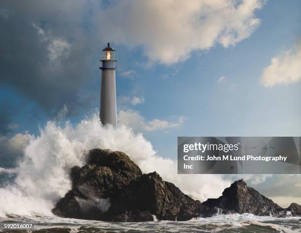 waves crashing on lighthouse and rock formations - felsen stock-fotos und bilder