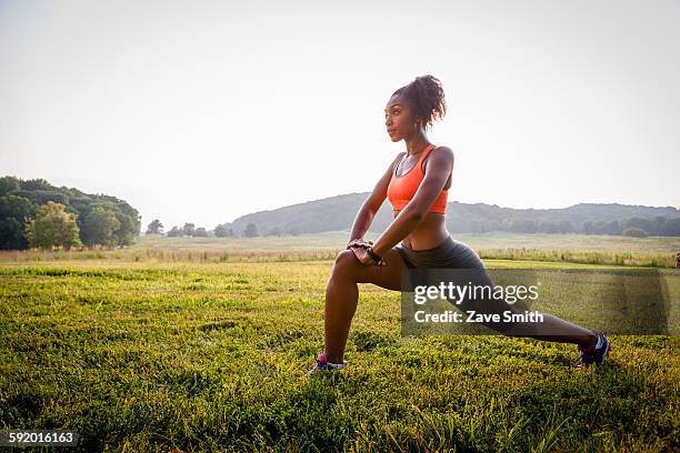 young female runner stretching in rural park - affondo foto e immagini stock