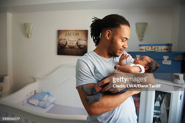 father cradling newborn baby in nursery - father stock pictures, royalty-free photos & images