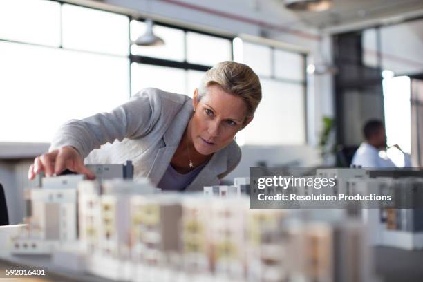 caucasian architect examining architectural model in office - architecture woman stockfoto's en -beelden