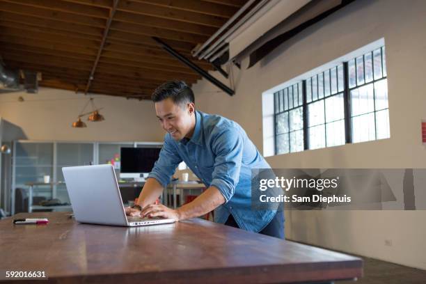 mixed race businessman working on laptop in office - samuser stock pictures, royalty-free photos & images