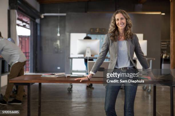 caucasian businesswoman smiling in office - leaning stock pictures, royalty-free photos & images