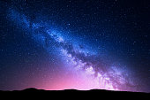 Milky Way and pink light at mountains. Night colorful landscape.