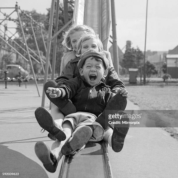 Children playing smiling going down a slide chute September 1955 at Beeston Notts