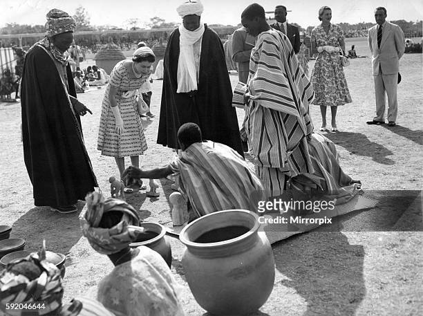 Queen Elizabeth II tour the model village at Children's rally held on the Kaduna Racecourse with Makaman Bida , left, pointing out various wooden...