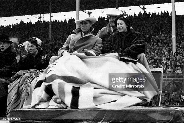Queen Elizabeth II, Princess Elizabeth and the Duke of Edinburgh sporting a "ten gallon hat" watching the rodeo at Calgary during their tour of...