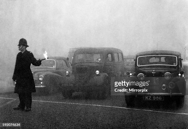 Policeman on point duty seen here using flares to guide the traffic during a heavy smog in London. 8th December 1952