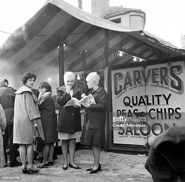 Jeanne Stather and Jennifer Fussey enjoy lunch time chips from the open air chip shop at the market. Hull, East Yorkshire. 16th March 1965.