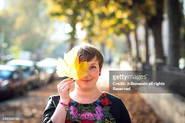 woman with a leave in her face autumn - jc bonassin stock-fotos und bilder