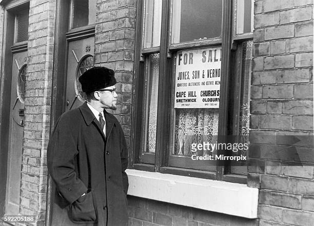 Malcolm X African-American Muslim minister and human rights activist smiles at a "for sale" notice in the window of number 66 Marshall Street in...
