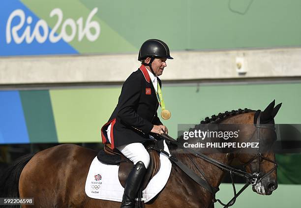 Britain's Nick Skelton on his horse Big Star rides with his gold medal after winning the individual equestrian show jumping event at the Olympic...