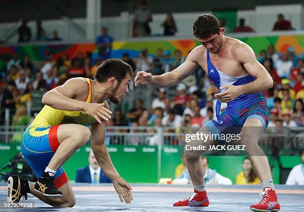 Kazakhstan's Nurislam Sanayev wrestles with Azerbaijan's Haji Aliyev in their men's 57kg freestyle repechage round 2 match on August 19 during the...