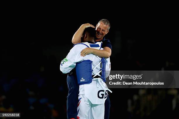 Lutalo Muhammad of Great Britain or Team GB celebrates with his coach after victory against Milad Beigi Harchegani of Azerbaijan during their Men's...