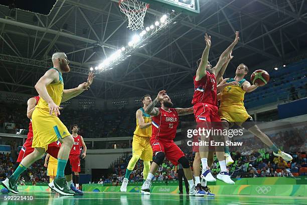 Joe Ingles of Australia makes a leaping pass around Milan Macvan of Serbia during the Men's Semifinal match on Day 14 of the Rio 2016 Olympic Games...
