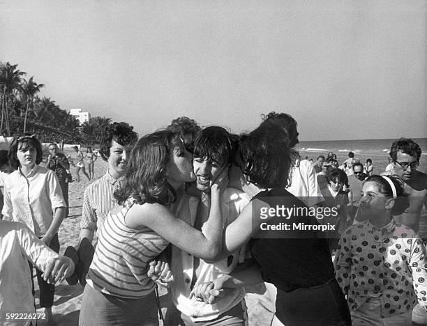 The Beatles in Miami Florida 18th February 1964. A kiss for Ringo - two high school girls sieze him as ge ran up the beach & smothered him with...