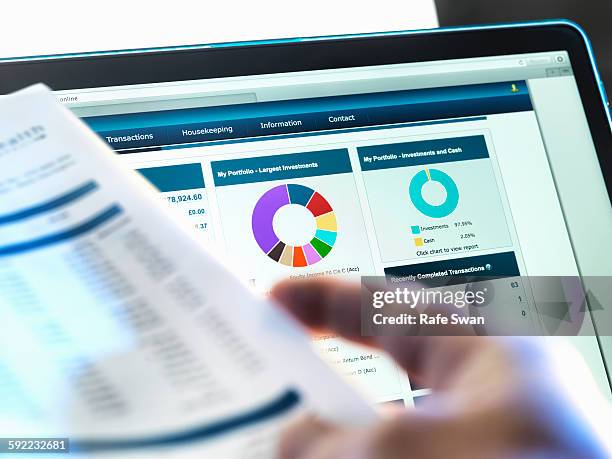 investor checking performance of financial portfolio online whilst reviewing investment statement - statement stockfoto's en -beelden