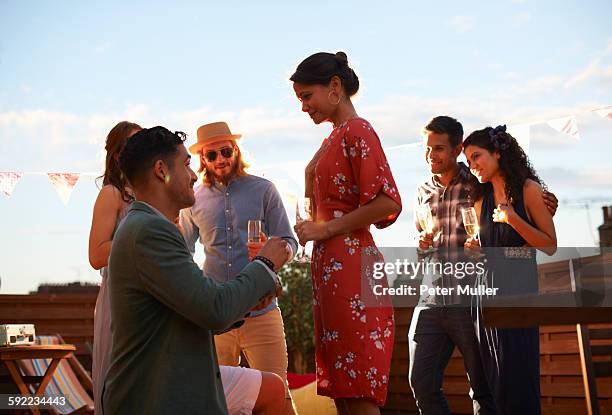 man proposing to woman on roof terrace, sunset in background - heiratsantrag stock-fotos und bilder
